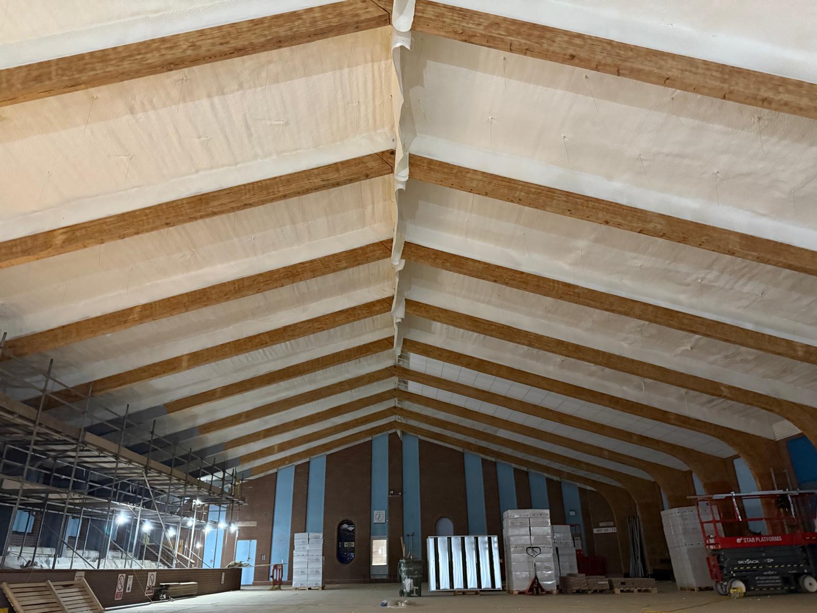 Spray foam applied to pool hall roof between glulam beams