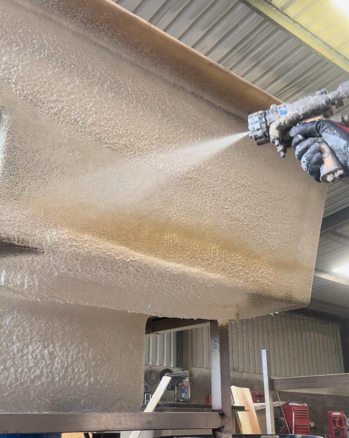 Spray gun applying foam to steel beam in pool hall